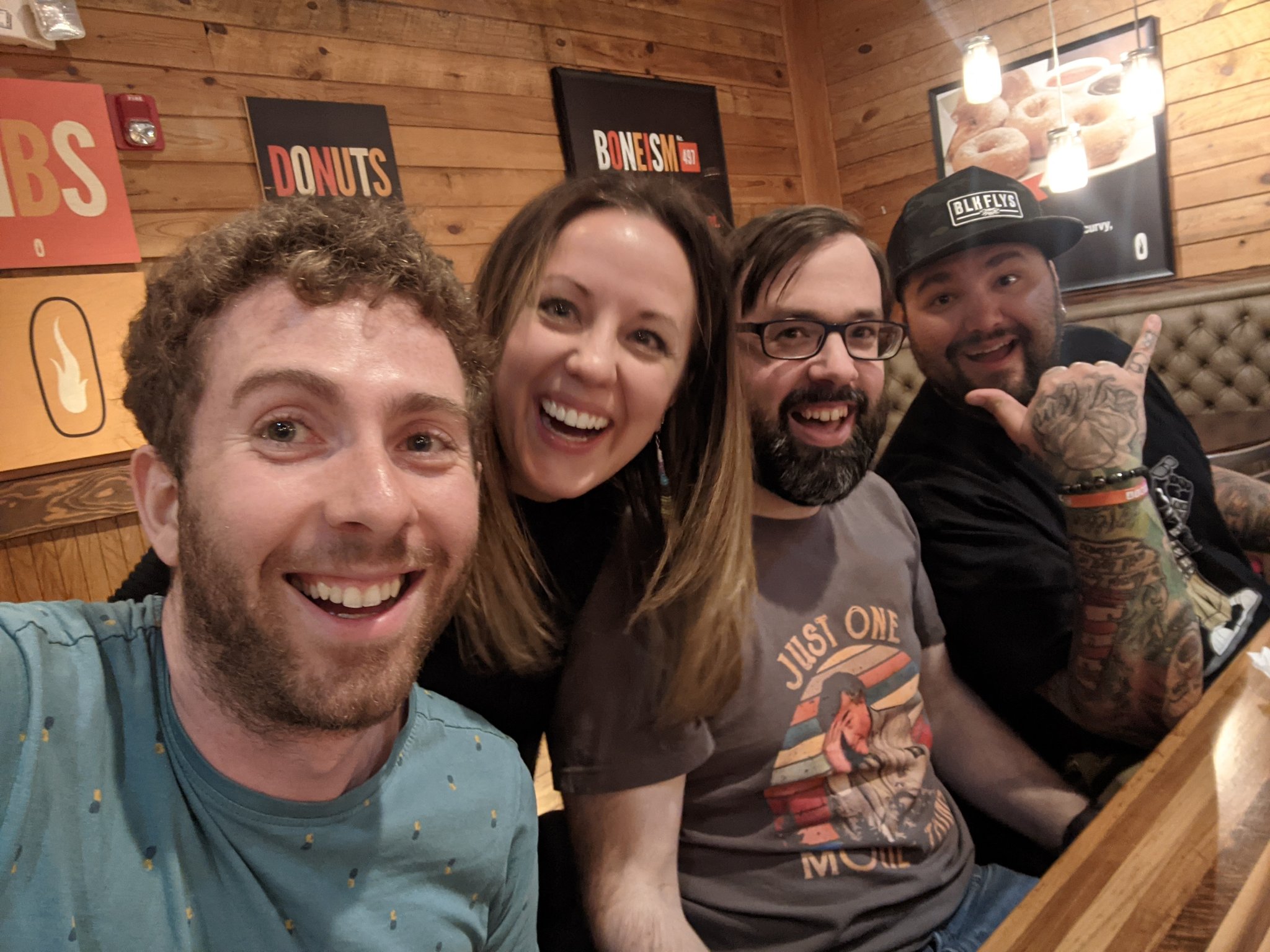 Selfie of four people smiling happily at a restaurant table.